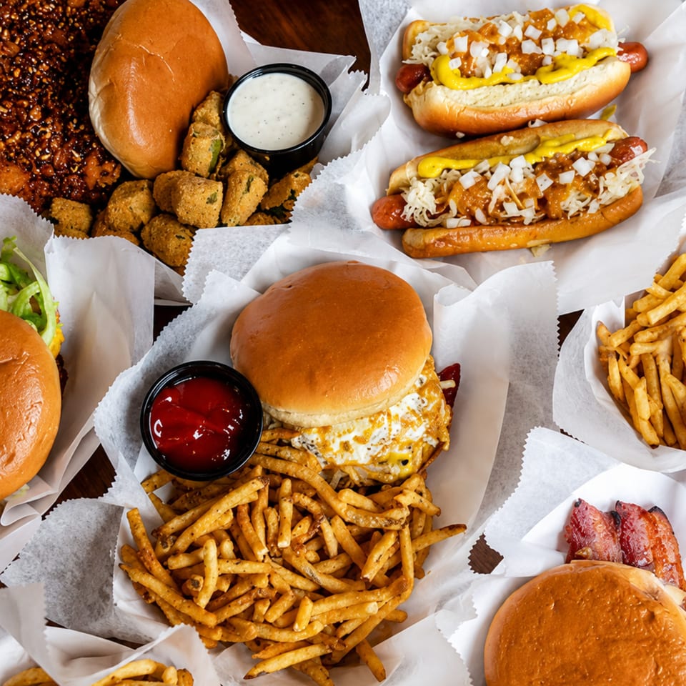 An overhead shot of various fast food items including burgers, hot dogs, fries, and fried okra.