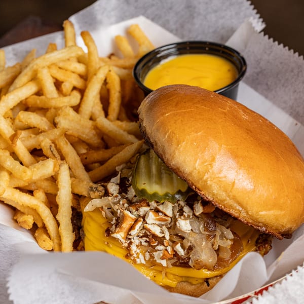 Cheeseburger with pickles, caramelized onions, pretzel bits, and fries with cheese sauce.